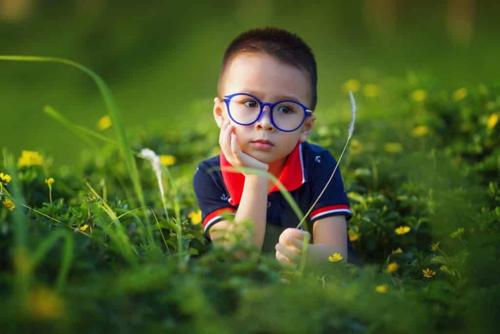 enfant sur l'herbe avec des lunettes bleue 